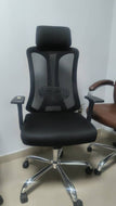 Black office chair with mesh back and chrome base in a room setting.