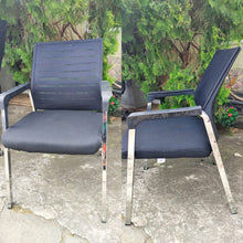 Load image into Gallery viewer, Two views of a black chair with metal frames on a concrete surface with greenery in the background.

