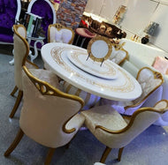 A white luxury marble dining table set with six beige fabric chairs, displayed in a showroom setting.